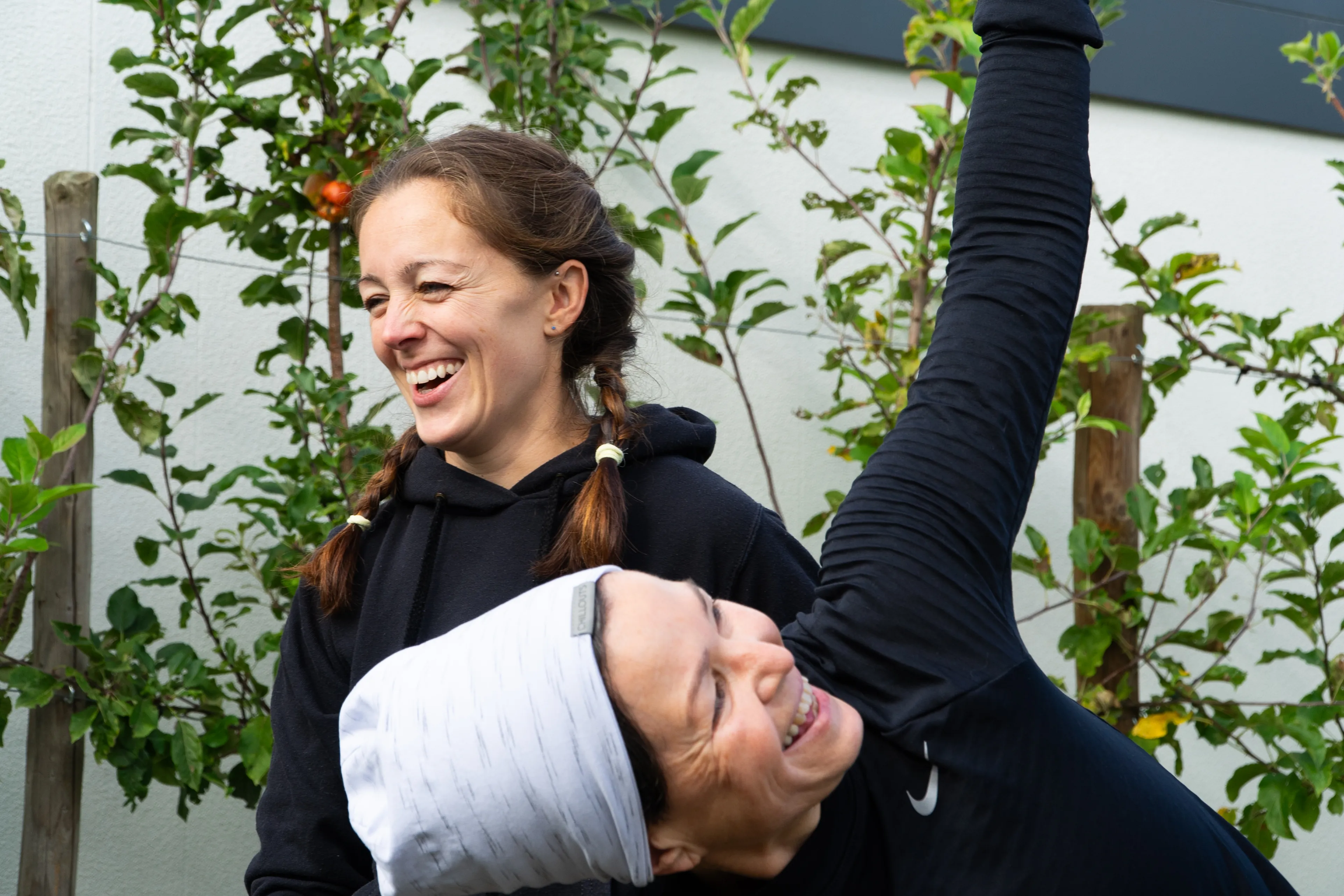 Melanie und Teilnehmerin lachen beim Power Yoga im Garten in Worms